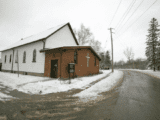 White clapboard and red brick church on snowy street
