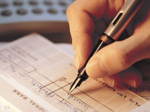 White person's hand writing a financial document with a fountain pen