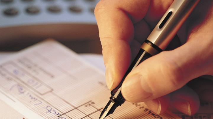 White person's hand writing a financial document with a fountain pen