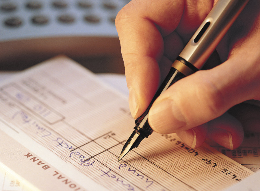 White person's hand writing a financial document with a fountain pen
