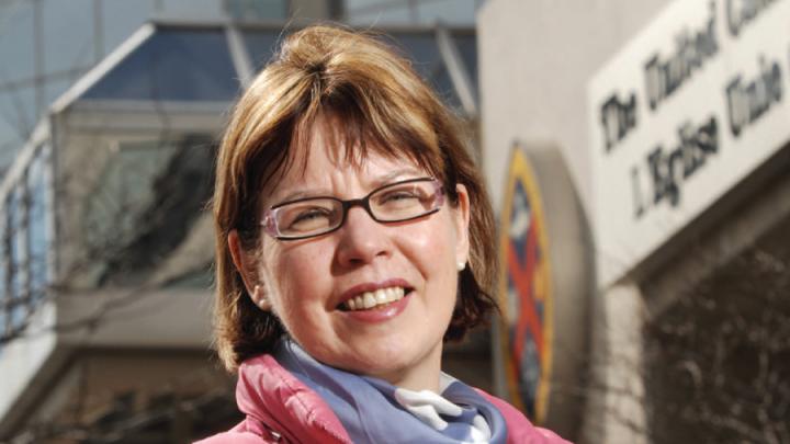 Red-haired white woman in pink parka looking at camera and smiling