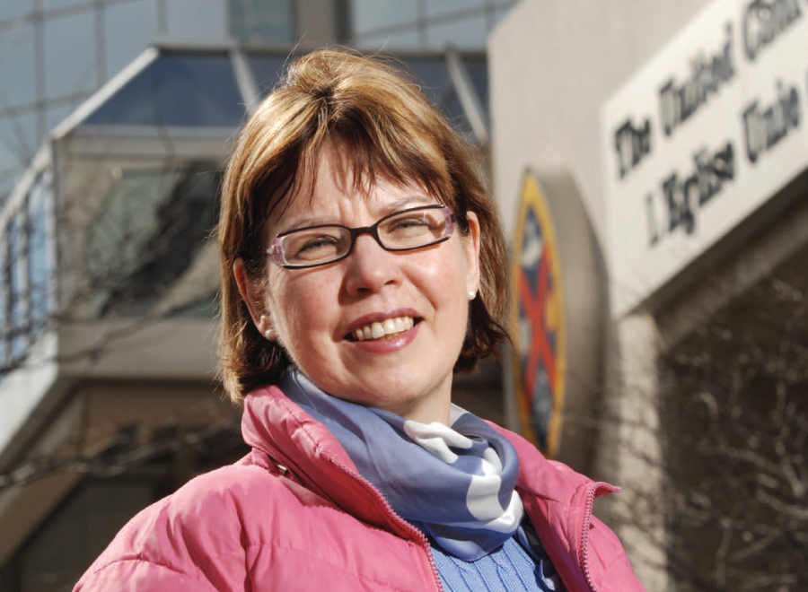 Red-haired white woman in pink parka looking at camera and smiling