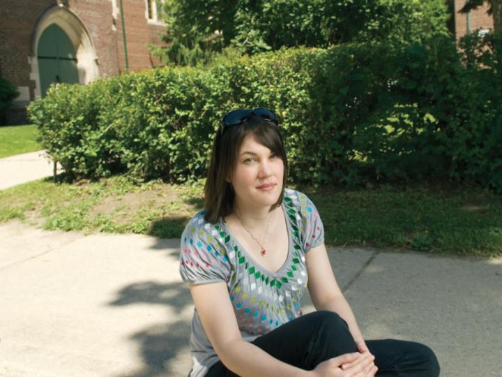 White woman with dark hair sitting on steps in front of church