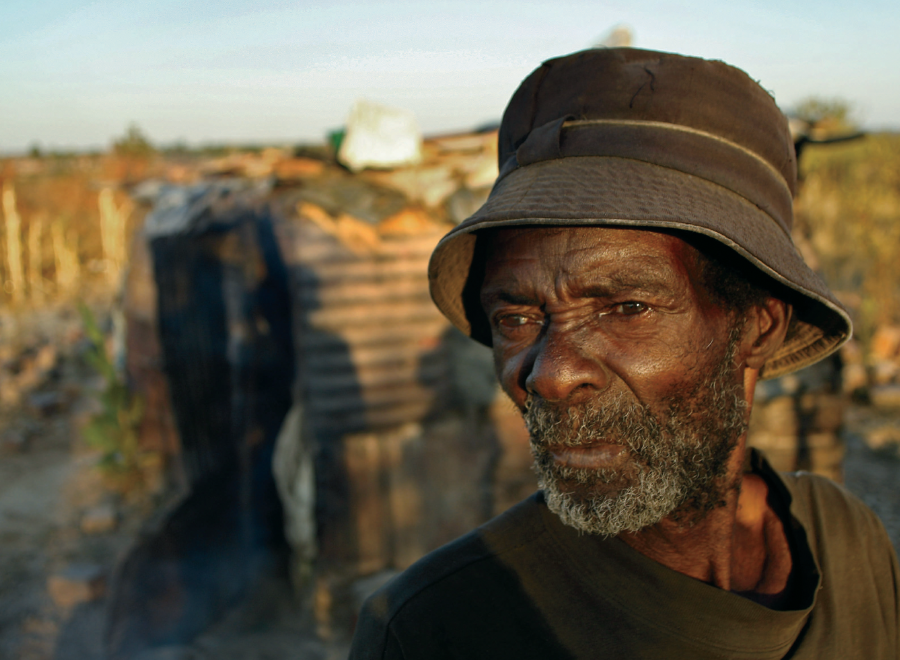 Elderly Black man in hat against African backdrop