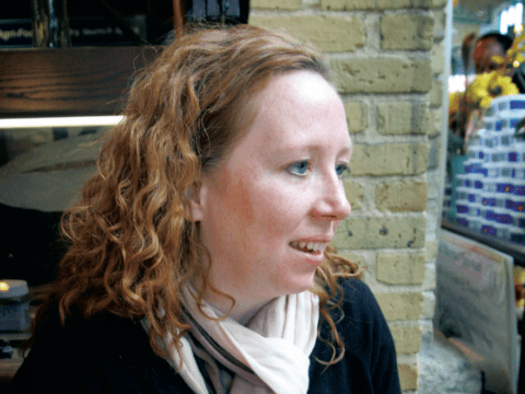 Young white red-haired women sitting in front of stone wall