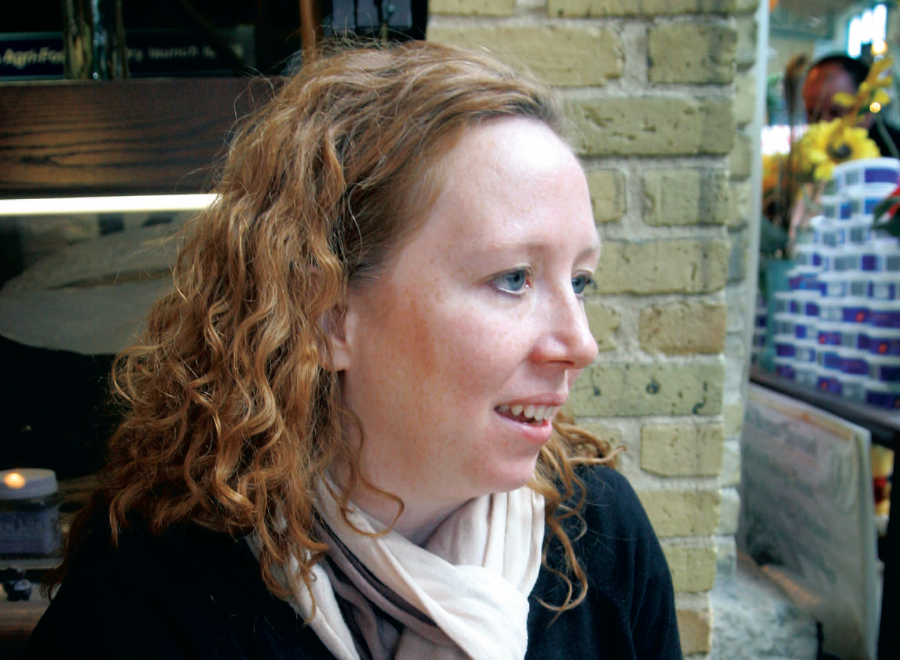 Young white red-haired women sitting in front of stone wall
