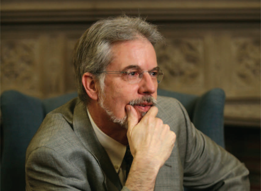 Grey-haired white man with glasses in suit and tie