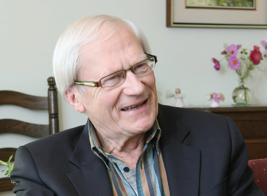 White-haired white man with glasses wearing striped shirt and dark jacket