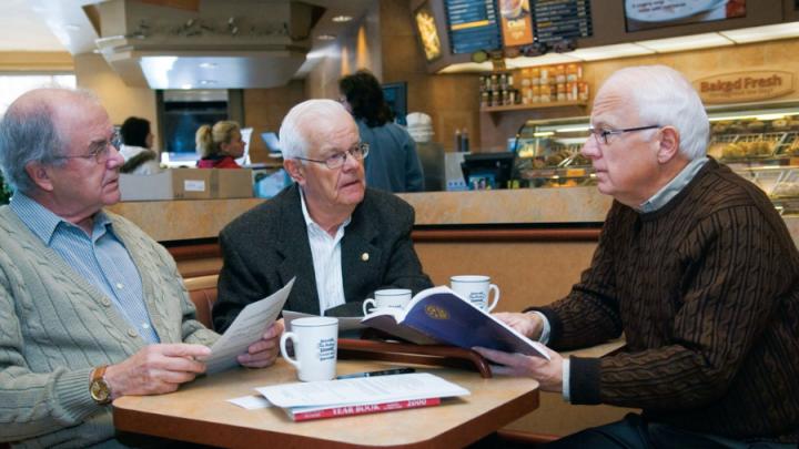 Three white-haired white men sitting at coffee shop