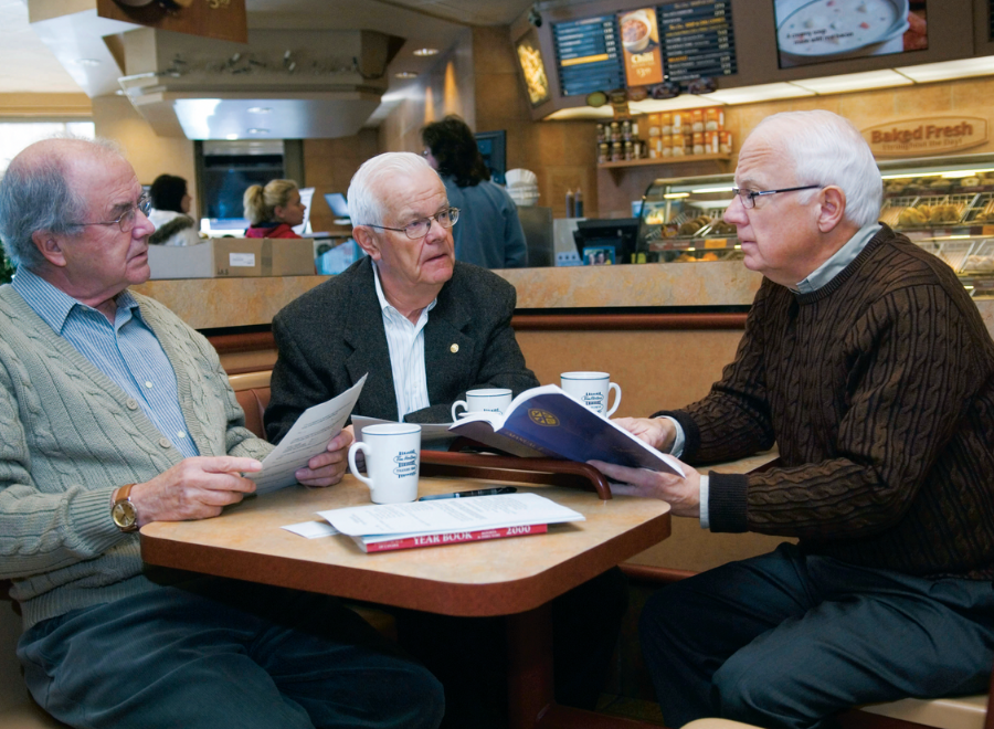 Three white-haired white men sitting at coffee shop