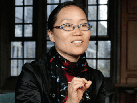 Chinese woman gesturing in front of old-style window