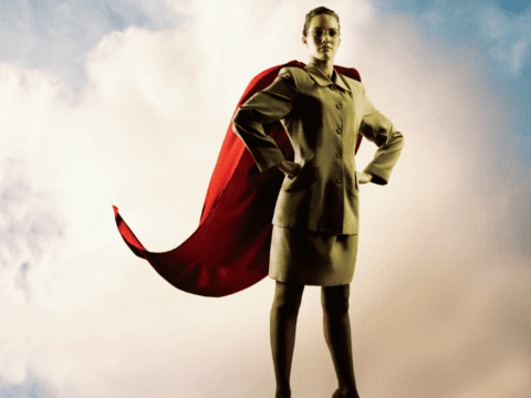 Young white woman in suit with red superhero cape