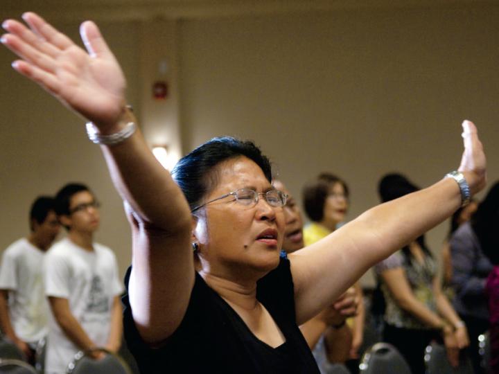Filipina with arms outstretched in prayer