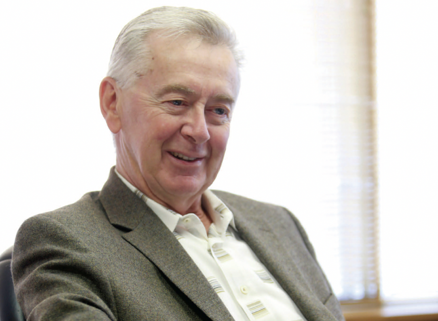 White-haired white man in suit jacket and open-necked white shirt