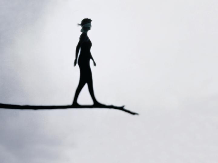 Illustration of blindfolded woman walking on tree branch