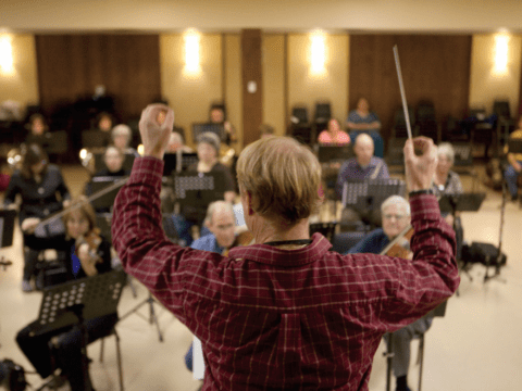 Conductor facing his orchestra, baton in the air