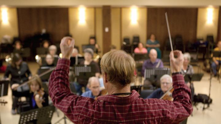 Conductor facing his orchestra, baton in the air