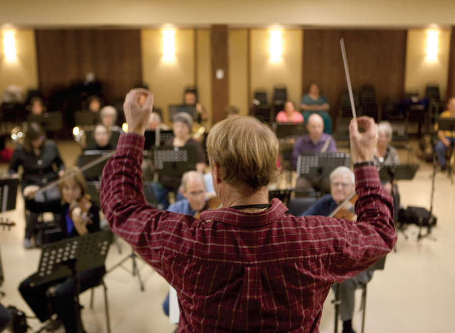 Conductor facing his orchestra, baton in the air