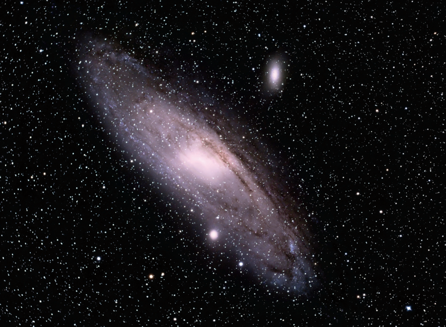 Photograph of Andromeda Galaxy with the stars of the universe in the background. The galaxy's many solar systems form a circular shape giving the impression that Andromeda is a shining whole in an endless field of the universe's mysterious vastness.