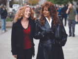 Two women walking on street, holding arms