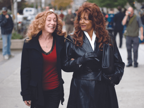Two women walking on street, holding arms