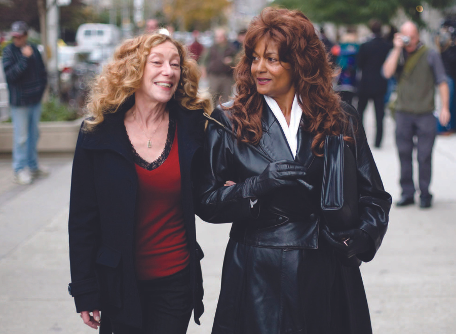 Two women walking on street, holding arms