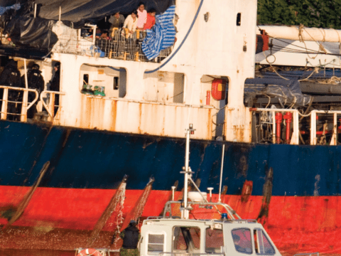 Family of migrants looking at police on ship