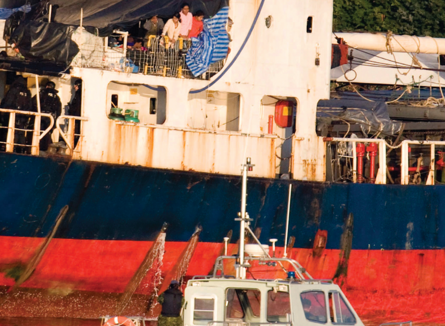 Family of migrants looking at police on ship