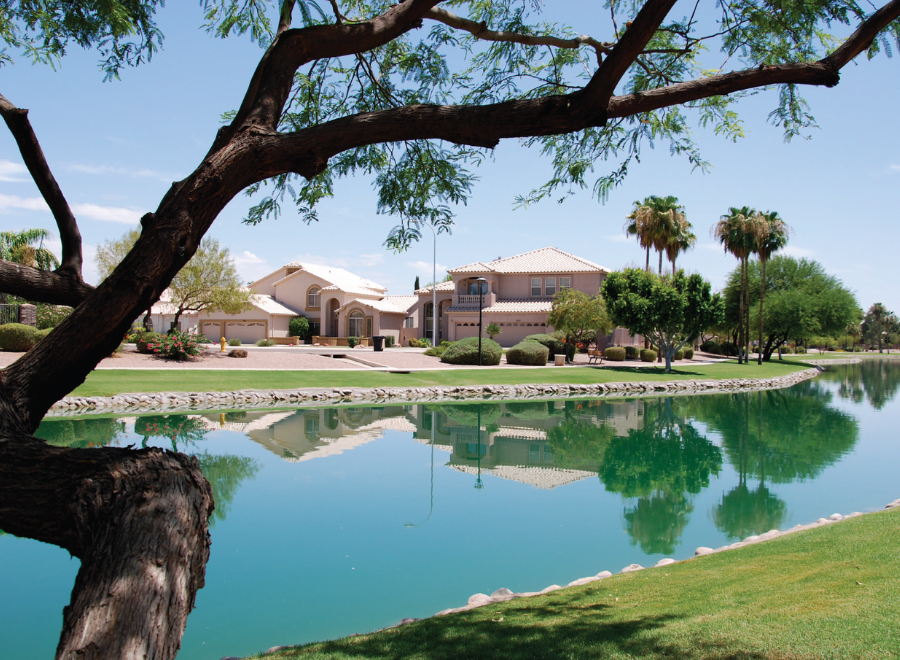 Landscape of monster home with lake in Tempe, Arizona. The lake is still, giving a near perfect reflection of the house