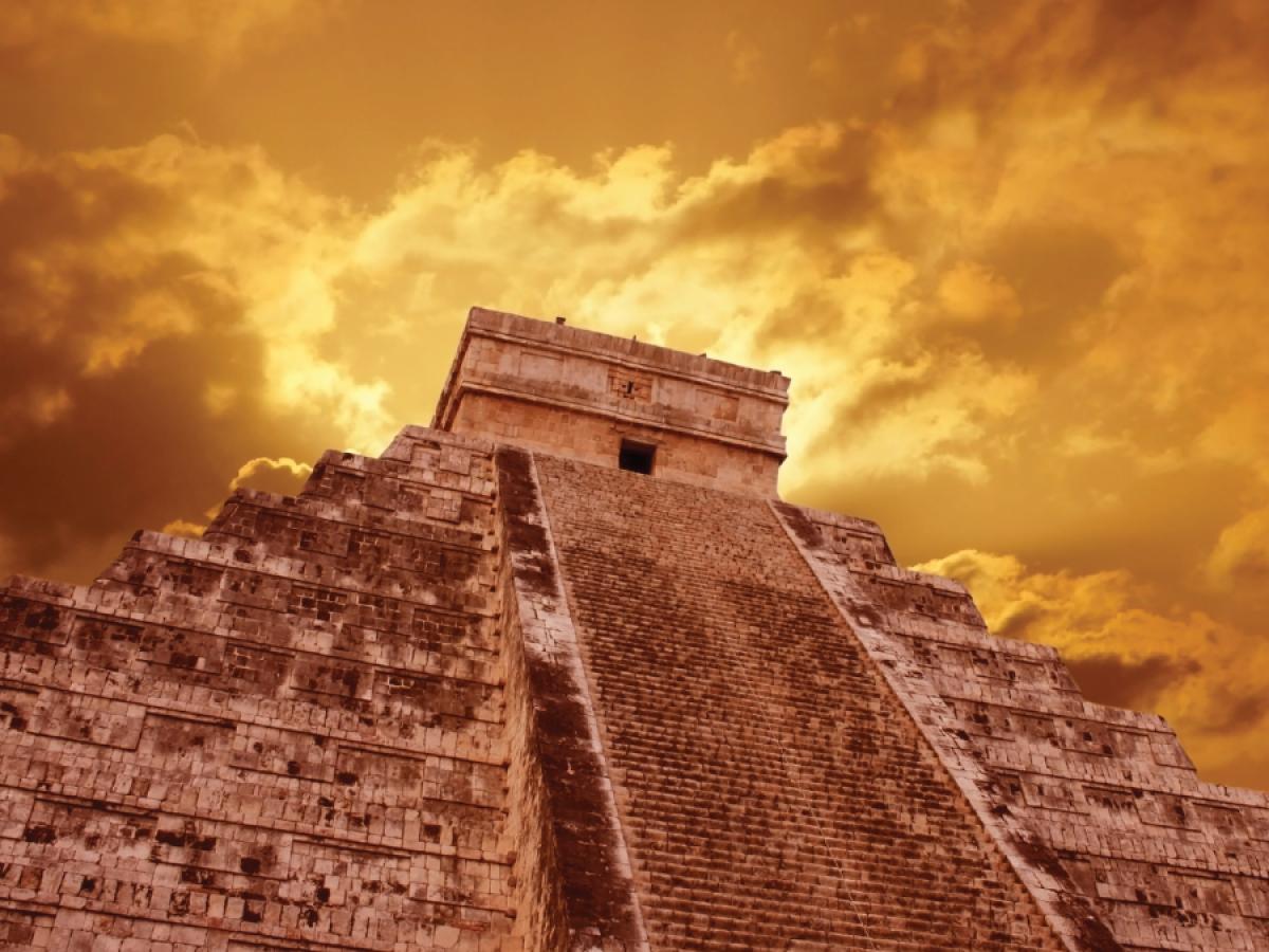 Mayan stone temple against cloudy sky. The photo is taken from the base of the structure, making it look either a touch ominous, or a bit heroic, depending on your mood.