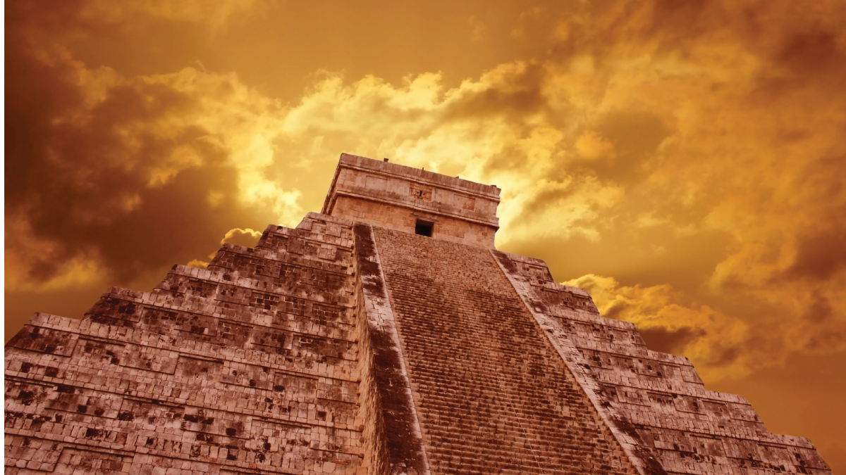 Mayan stone temple against cloudy sky. The photo is taken from the base of the structure, making it look either a touch ominous, or a bit heroic, depending on your mood.