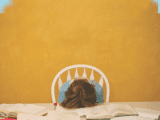 student with head down on books