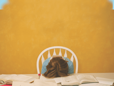 student with head down on books