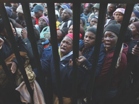refugees crowd against a fence in South Africa