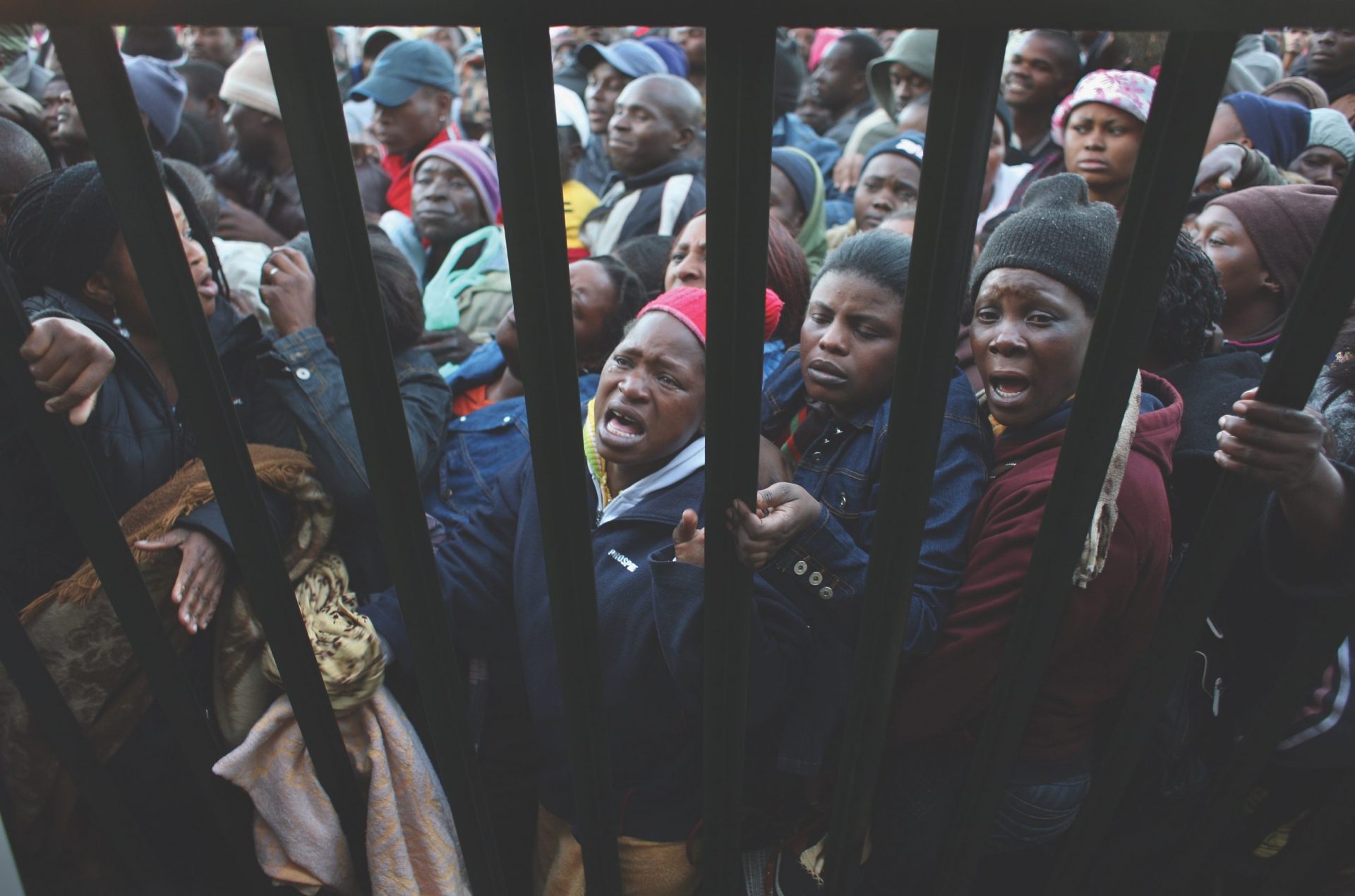 refugees crowd against a fence in South Africa