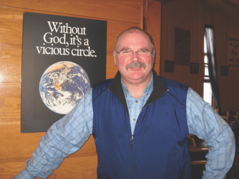 Man with glasses and mustache looks at camera