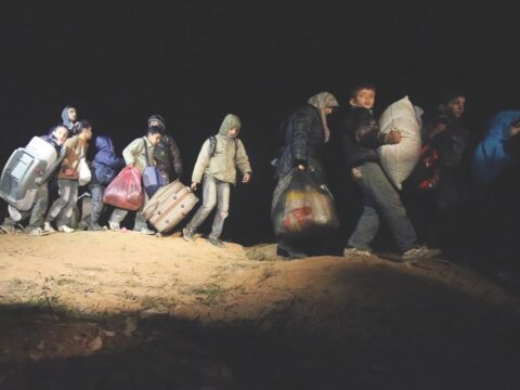 string of people walking with belongings