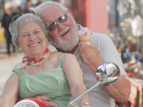 white-haired man and woman on red motorbike