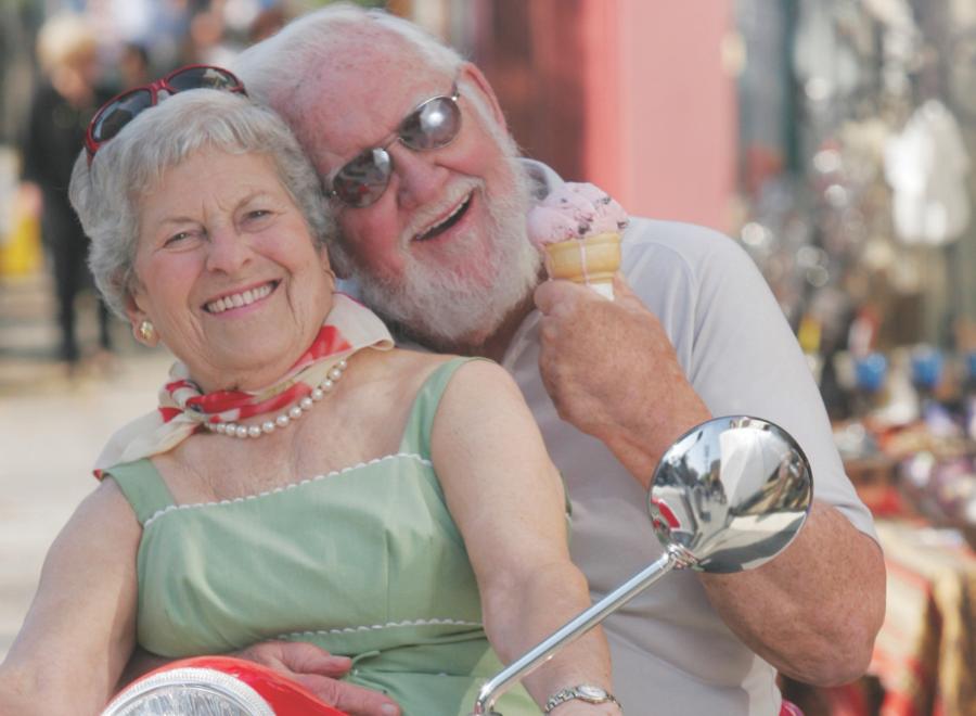 white-haired man and woman on red motorbike