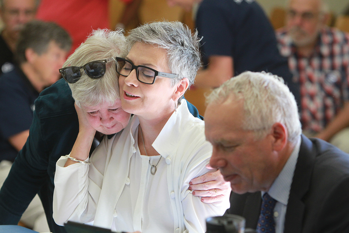 Atheist minister Gretta Vosper receives a hug from Fran Ota, also a United Church minister, before the start of the Toronto Conference sub-Executive meeting, held on Sept. 15. Vosper’s lawyer, Julian Falconer, sits to her left. Photo by Hugh Wesley