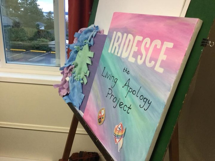 A canvas painted with the words, "Iridesce: The Living Apology Project."