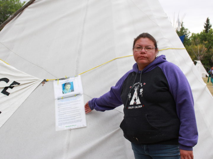 Richelle Dubois stands beside a sign discussing the issues in the police investigation into the death of her son, Haven, at the Justice for Our Stolen Children protest camp in Regina, Sask., on Sept. 2, 2018. (Photo: Alexa Lawlor)