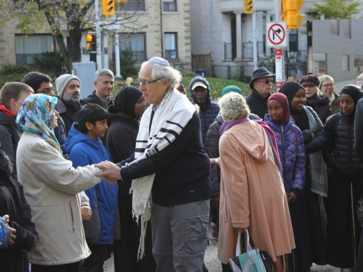 A member of the Holy Blossom Temple shakes hands with those have come to show their support in the wake of the synagogue shooting in Pittsburgh. (Credit: Amy van den Berg)