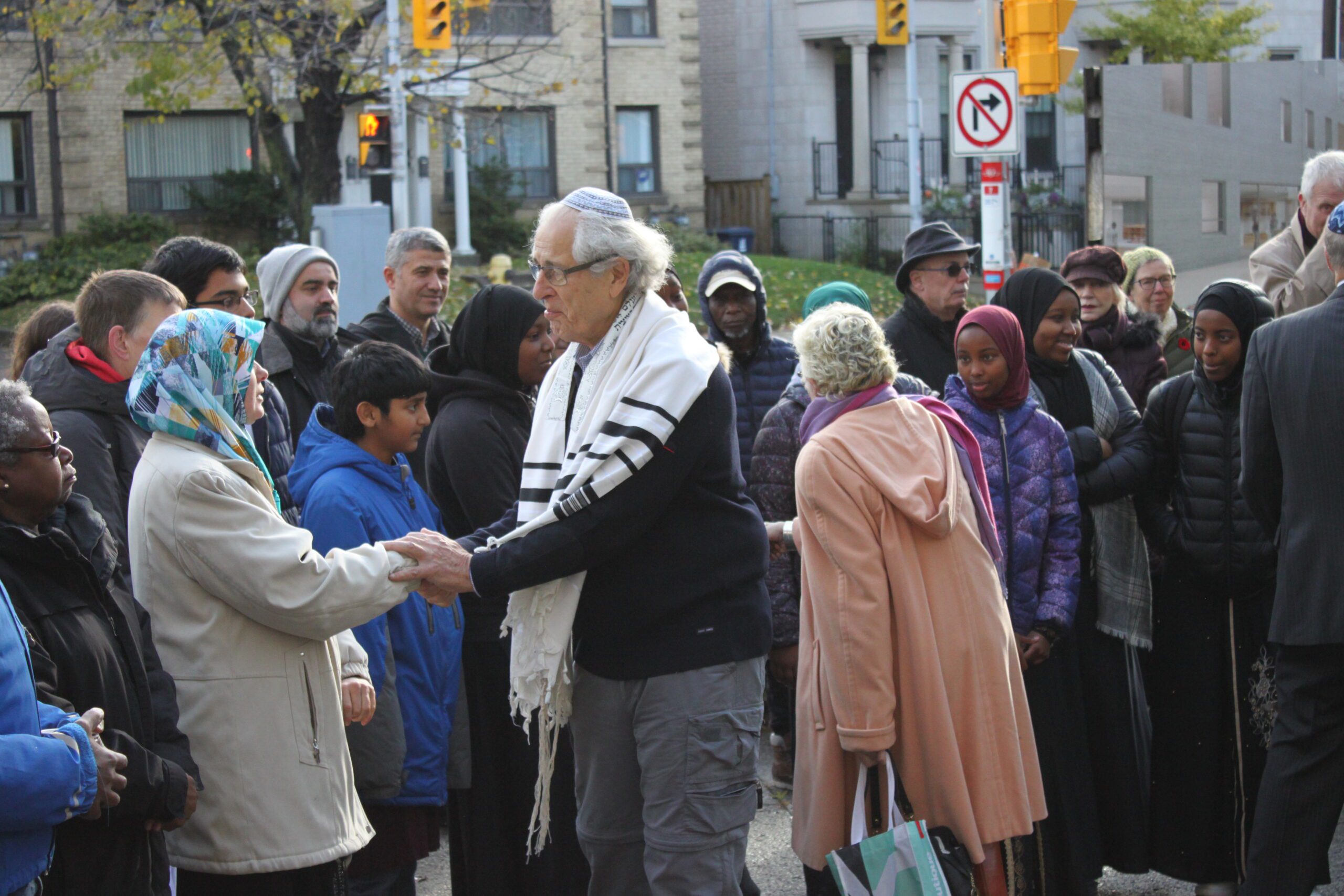 A member of the Holy Blossom Temple shakes hands with those have come to show their support in the wake of the synagogue shooting in Pittsburgh. (Credit: Amy van den Berg)