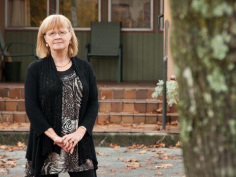 Bernadette stands in front of the former Burnaby Home for Girls, which is now a L'Arche community for people with developmental disabilities. Photo by Marlis Funk