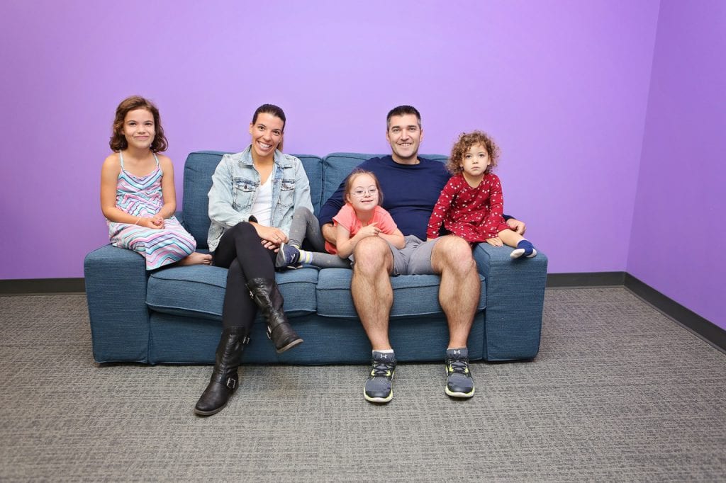 Family, including three daughters, one with Down syndrome, poses on couch