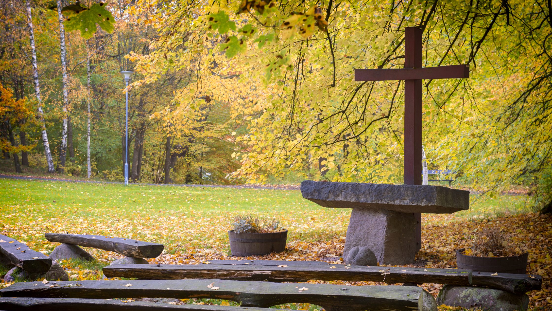 Outdoor church. Wooden seats in front of a stone altar with a red cross.