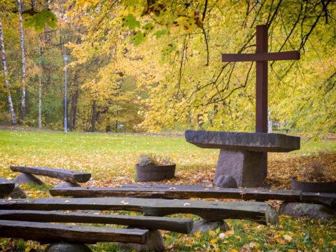 Outdoor church. Wooden seats in front of a stone altar with a red cross.