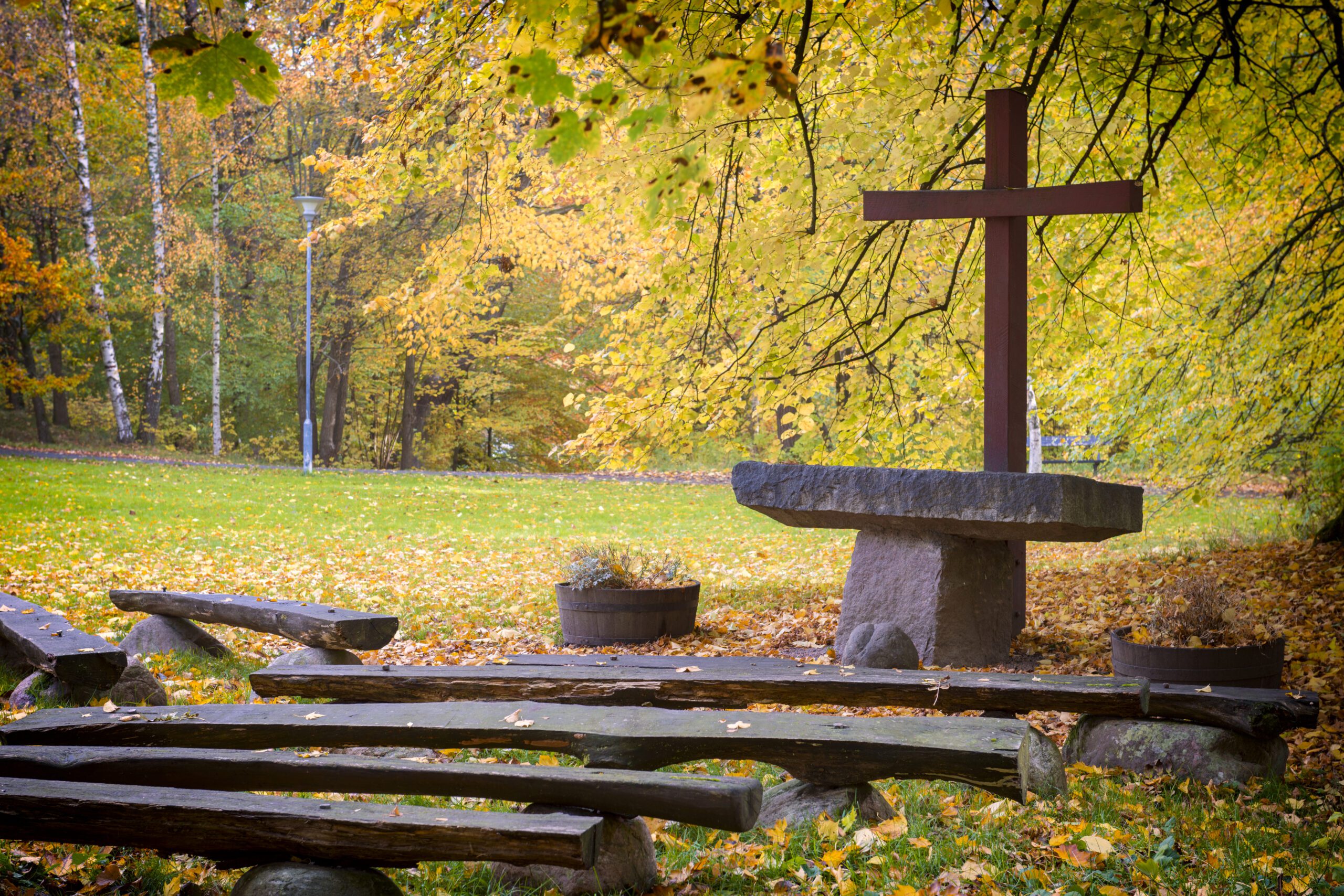 Outdoor church. Wooden seats in front of a stone altar with a red cross.