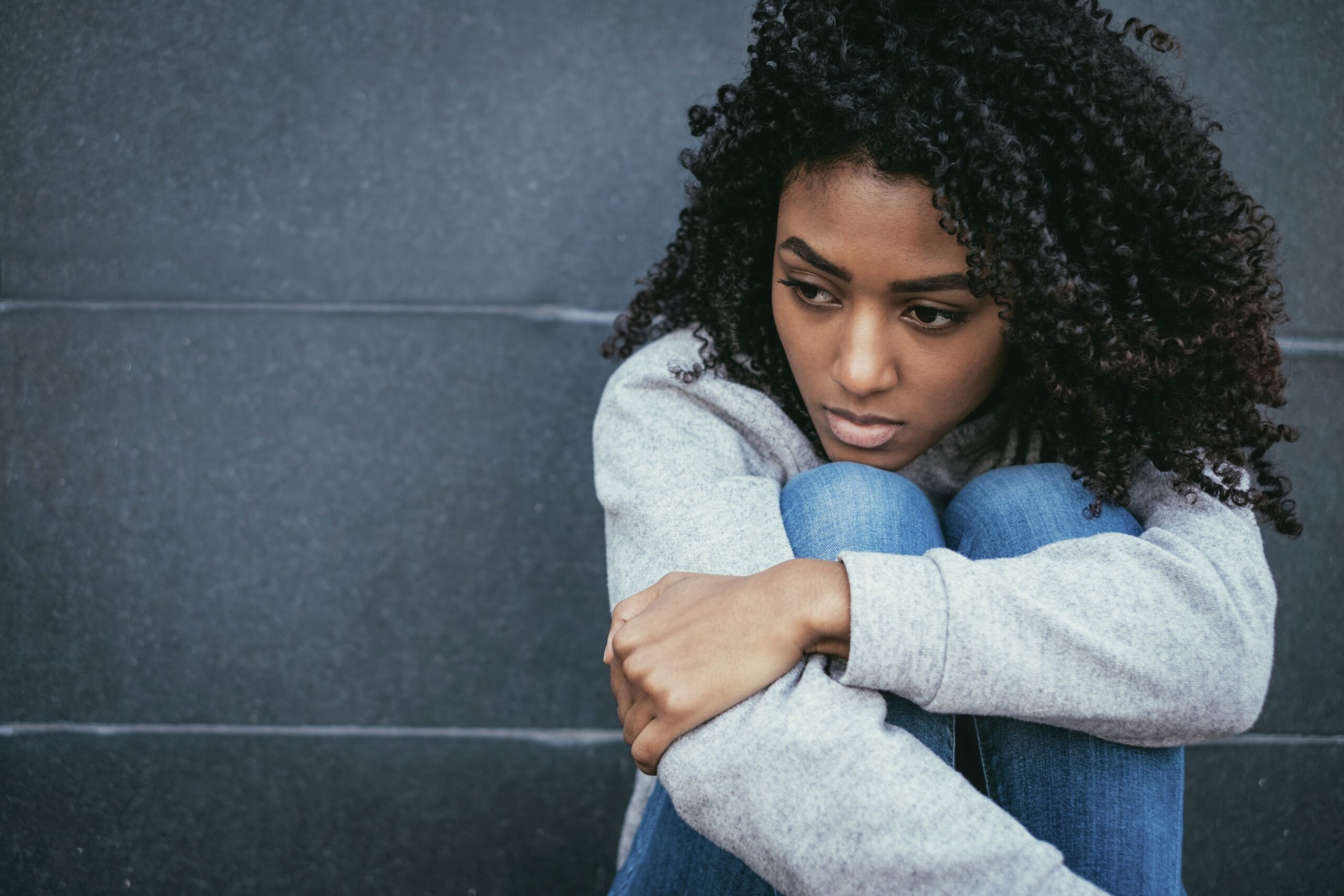 An upset woman sits, huddled.
